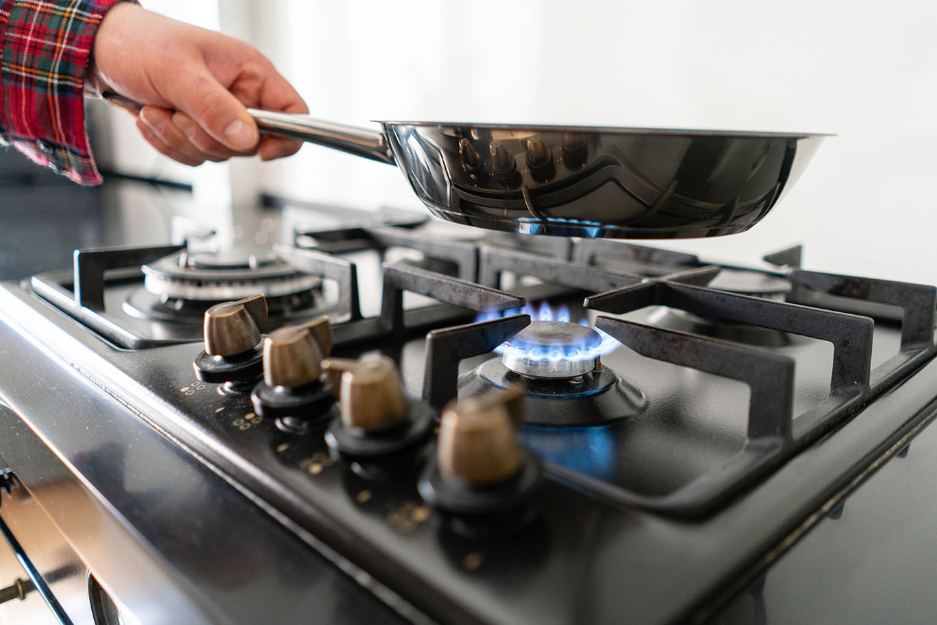 A man cooks in a frying pan, puts it on the stove.
