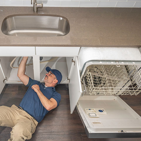 man installing a dishwasher in kitchen